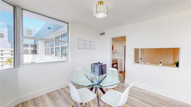 dining room with light wood finished floors, baseboards, and visible vents