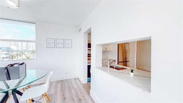 dining space featuring light wood-style flooring, a view of city, visible vents, and baseboards