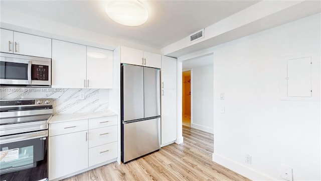 kitchen featuring stainless steel fridge, visible vents, light wood-style floors, white cabinetry, and backsplash