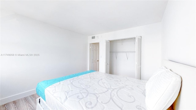 bedroom featuring baseboards, a closet, visible vents, and wood finished floors