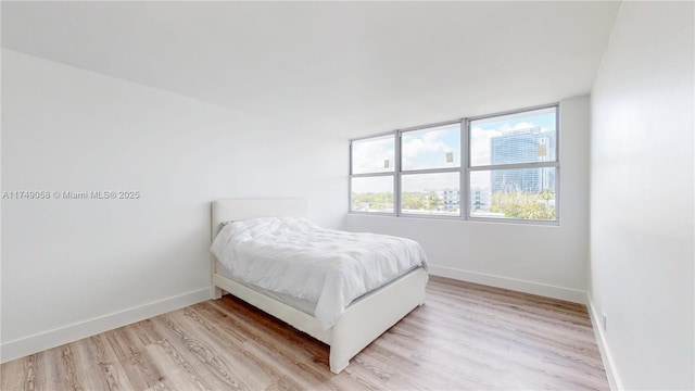 bedroom featuring light wood finished floors and baseboards