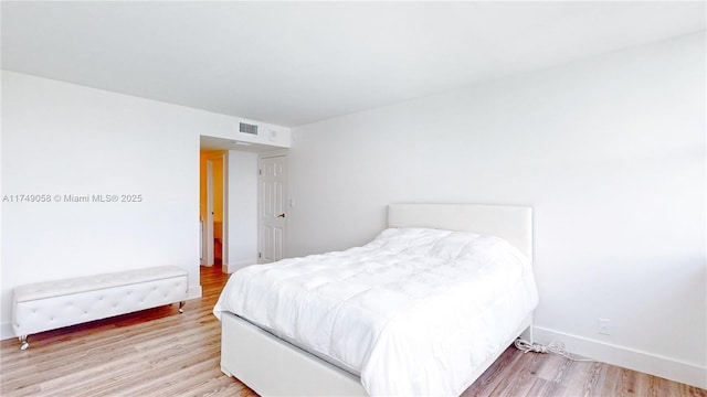 bedroom with light wood-style floors, visible vents, and baseboards