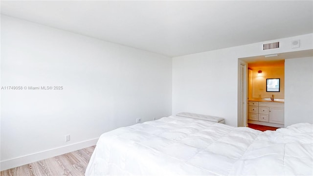 bedroom featuring visible vents, a sink, light wood-style flooring, and baseboards