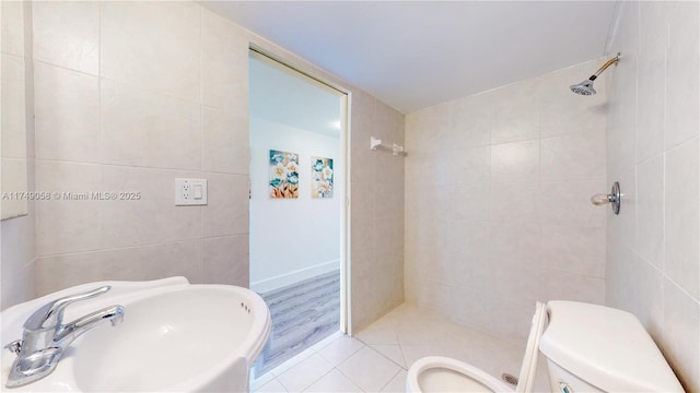 full bath featuring tile walls, a sink, a tile shower, and toilet