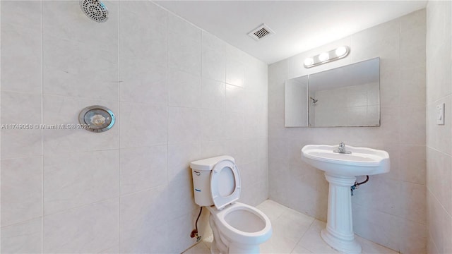 full bath featuring visible vents, toilet, and tile walls