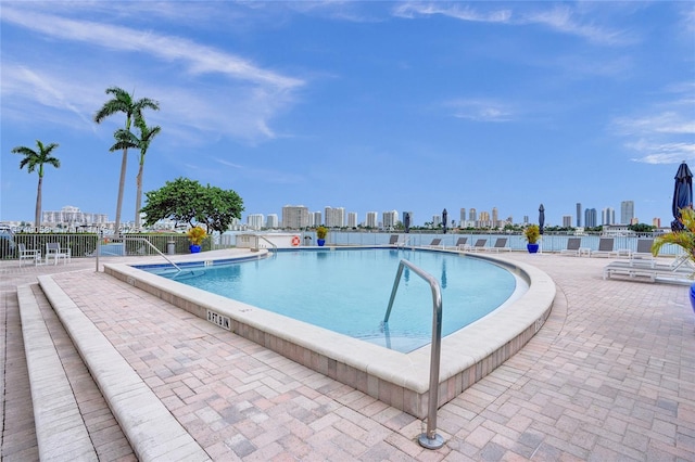 pool with a view of city, a patio area, and fence