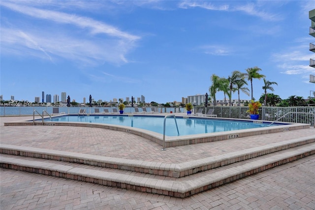 community pool with a city view and fence