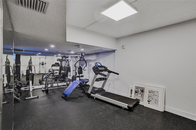 exercise room with visible vents, a textured ceiling, and baseboards