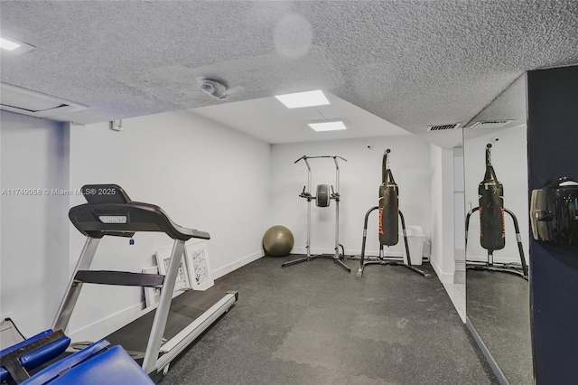 exercise room with visible vents, a textured ceiling, and baseboards