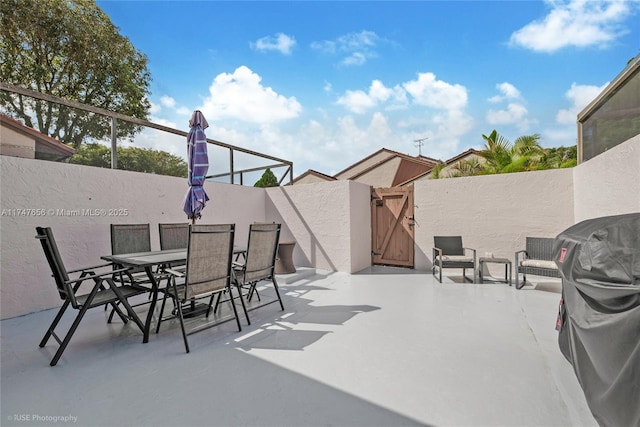 view of patio featuring outdoor dining space, a gate, and fence