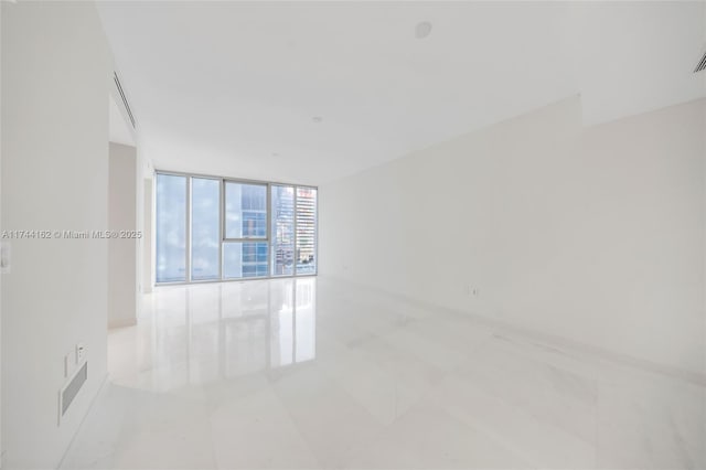 unfurnished room with expansive windows and visible vents