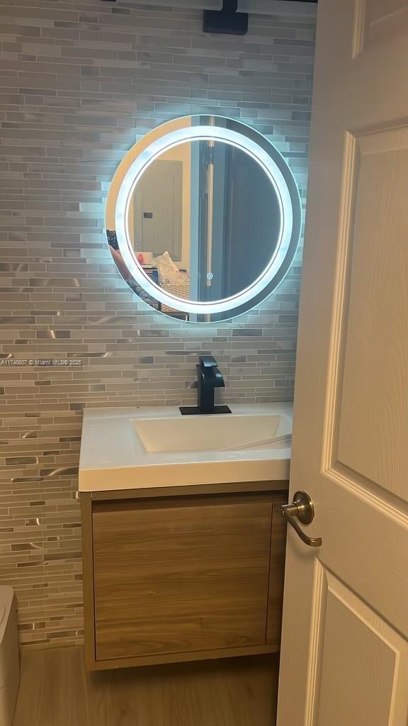 22511 SW 88th Pl, Cutler Bay, FL 33190 - half bath with tasteful backsplash, wood finished floors, and vanity