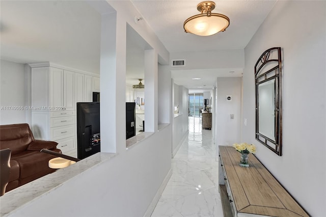 hall featuring visible vents, baseboards, and marble finish floor