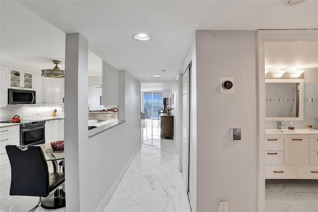 hallway with a sink, baseboards, marble finish floor, and recessed lighting