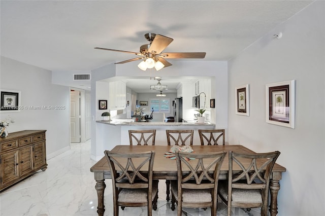 dining space featuring ceiling fan with notable chandelier, baseboards, visible vents, and marble finish floor