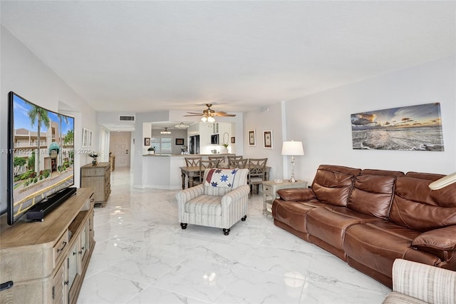 living area featuring visible vents, marble finish floor, and a ceiling fan