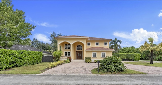 mediterranean / spanish home with a tiled roof, fence, a porch, and stucco siding