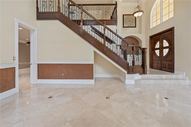 foyer entrance featuring marble finish floor, stairs, a high ceiling, and baseboards