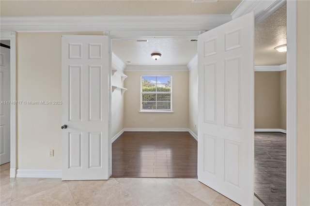 spare room featuring crown molding, a textured ceiling, baseboards, and light tile patterned floors