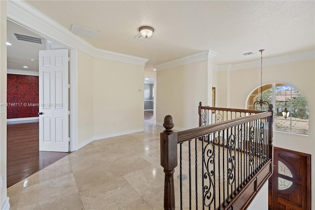 hallway with baseboards, crown molding, visible vents, and an upstairs landing