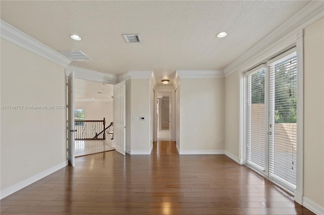 spare room with dark wood-style floors, visible vents, crown molding, and a textured ceiling