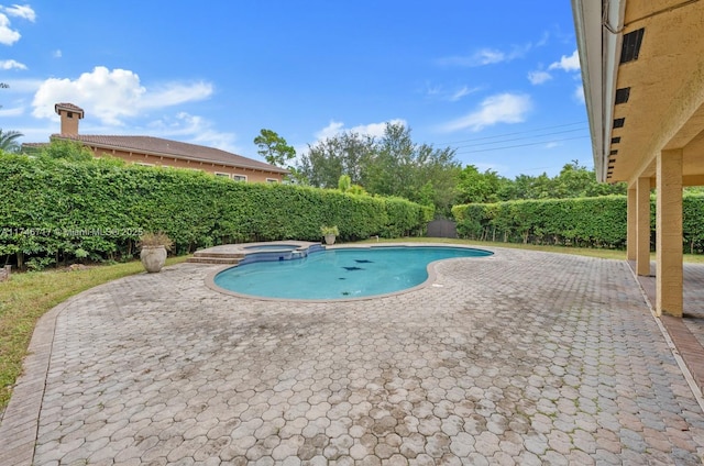 view of swimming pool featuring a patio, a fenced backyard, and a pool with connected hot tub