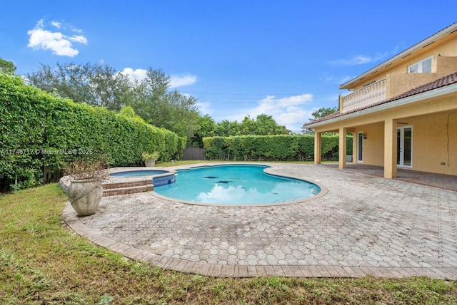 view of swimming pool with a pool with connected hot tub, a fenced backyard, and a patio