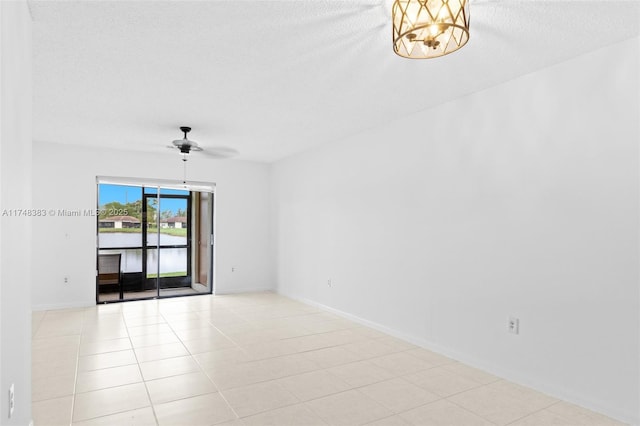 unfurnished room with light tile patterned floors, baseboards, a ceiling fan, and a textured ceiling