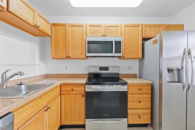 kitchen featuring appliances with stainless steel finishes, light countertops, a sink, and light brown cabinets