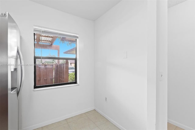 spare room with light tile patterned floors and baseboards