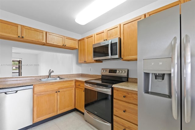 kitchen with a sink, stainless steel appliances, light countertops, and light brown cabinetry