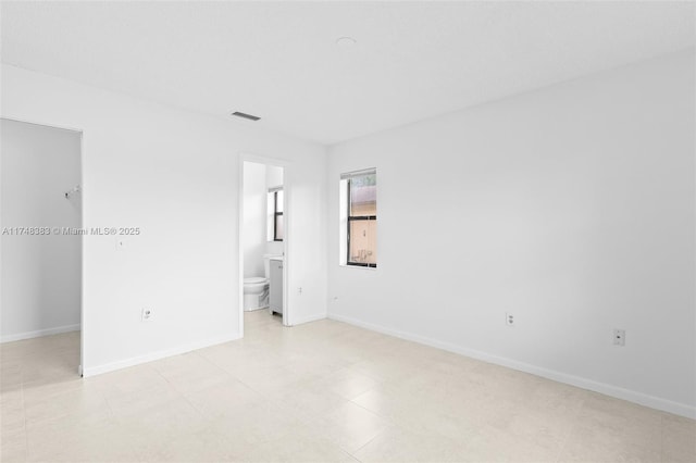 unfurnished bedroom featuring a walk in closet, a closet, visible vents, connected bathroom, and baseboards