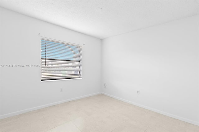 unfurnished room featuring a textured ceiling and baseboards