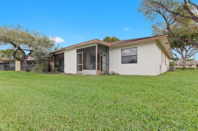 rear view of property featuring a lawn, fence, a sunroom, and stucco siding