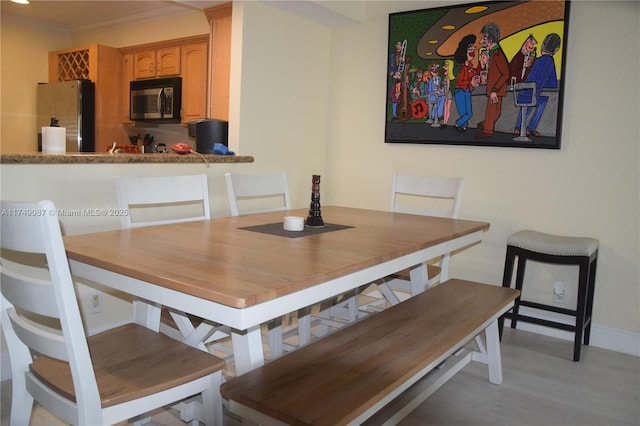 dining space with light wood finished floors, baseboards, and ornamental molding