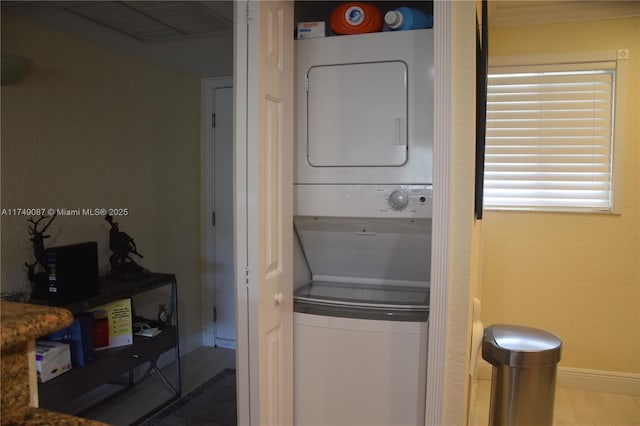 washroom with stacked washer / dryer, laundry area, visible vents, and baseboards