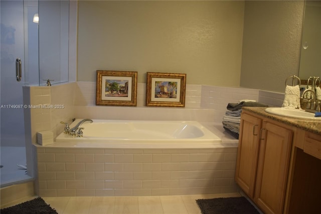 bathroom featuring a stall shower, tile patterned flooring, a garden tub, and vanity