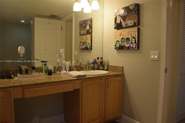 full bathroom featuring a textured wall, visible vents, a sink, and double vanity