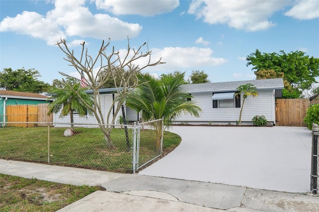 view of front of property with a fenced front yard, driveway, and a front lawn