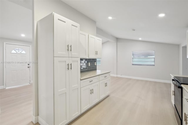 3883 Chickasha Rd, Lake Worth, FL 33462 - kitchen featuring electric range, light wood-style flooring, light countertops, backsplash, and white cabinetry
