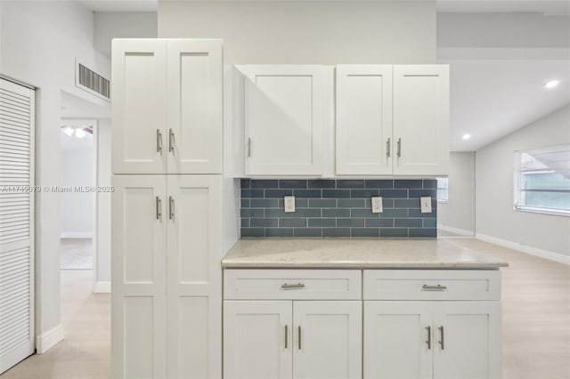 3883 Chickasha Rd, Lake Worth, FL 33462 - kitchen with white cabinetry, backsplash, and light stone countertops