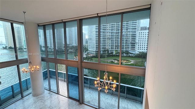 interior space with a chandelier, a view of city, marble finish floor, and a water view