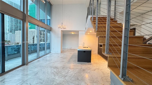 interior space with marble finish floor, a high ceiling, an inviting chandelier, a sink, and stairs