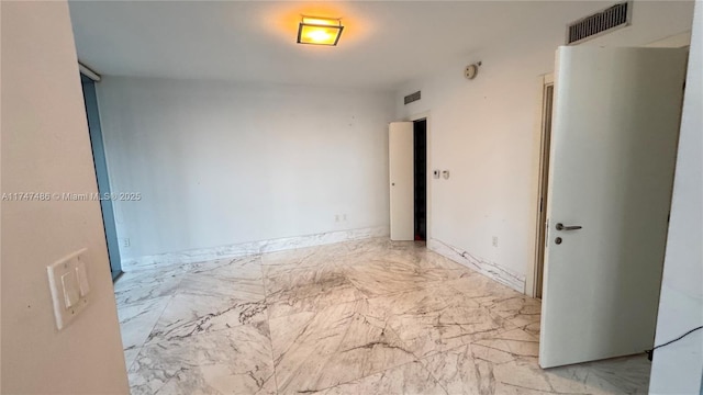 unfurnished room with marble finish floor, visible vents, and baseboards