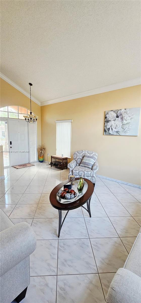 18860 NW 12th St, Pembroke Pines, FL 33029 - living room featuring crown molding, a textured ceiling, and a chandelier