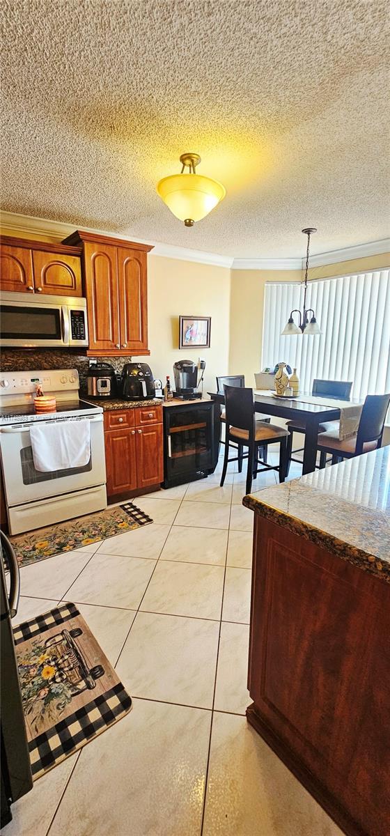 18860 NW 12th St, Pembroke Pines, FL 33029 - kitchen featuring white range with electric stovetop, stainless steel microwave, ornamental molding, a textured ceiling, and tasteful backsplash