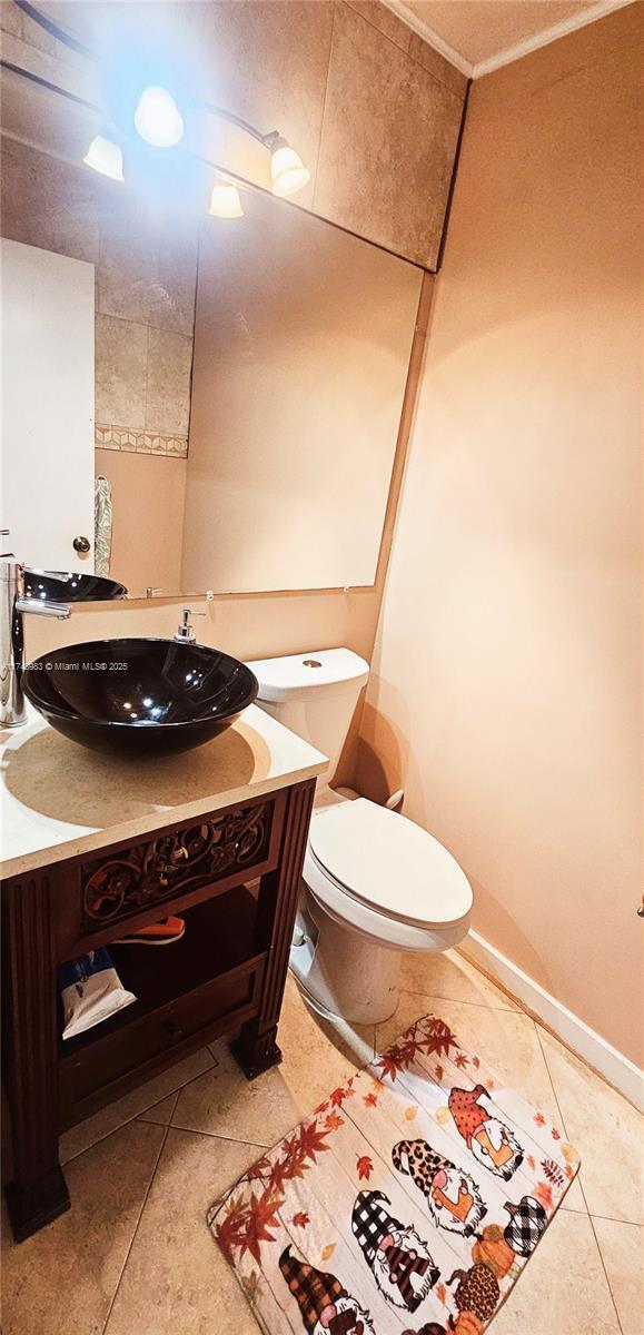 bathroom with baseboards, vanity, toilet, and tile patterned floors