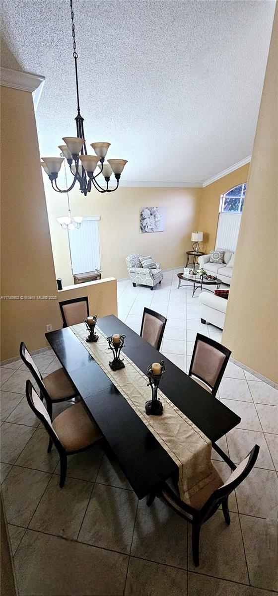 dining area featuring a textured ceiling, light tile patterned flooring, and an inviting chandelier