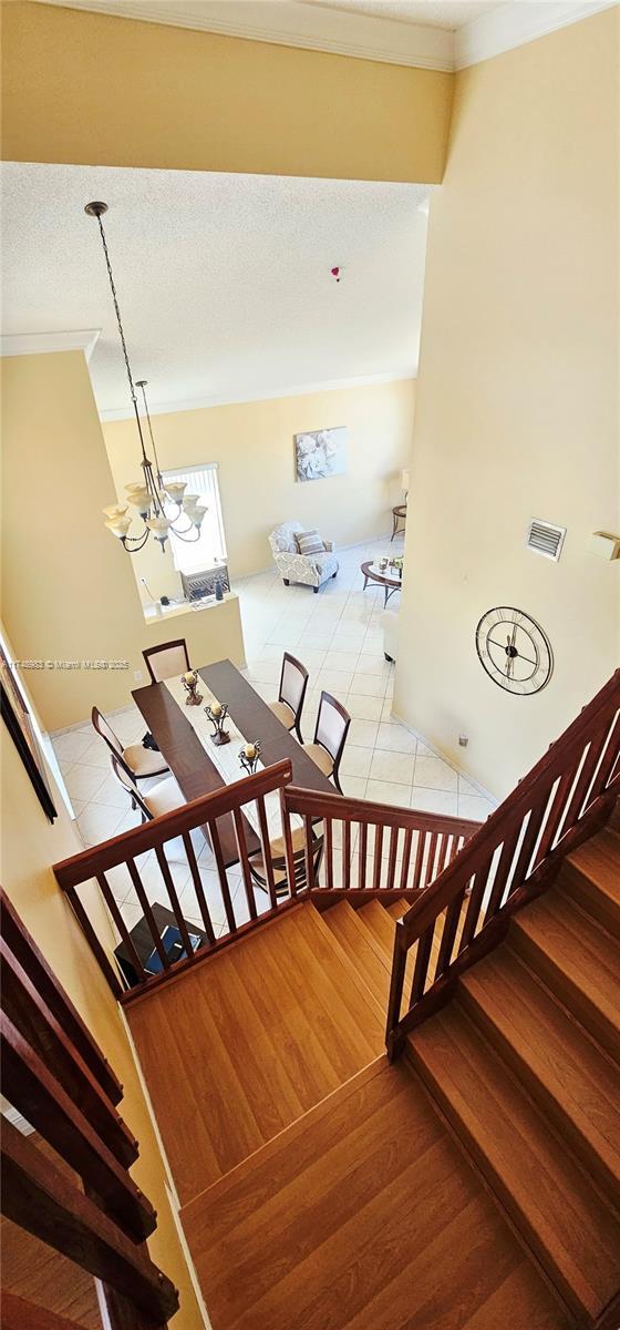 18860 NW 12th St, Pembroke Pines, FL 33029 - staircase with wood finished floors, crown molding, a chandelier, and a textured ceiling