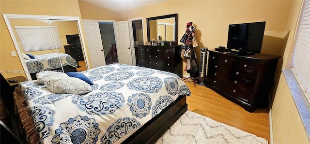 bedroom featuring vaulted ceiling, a closet, and light wood-style flooring